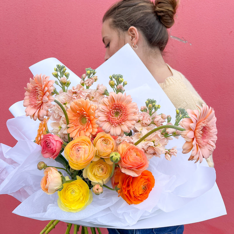 Peach and orange bouquet wrapped in white paper