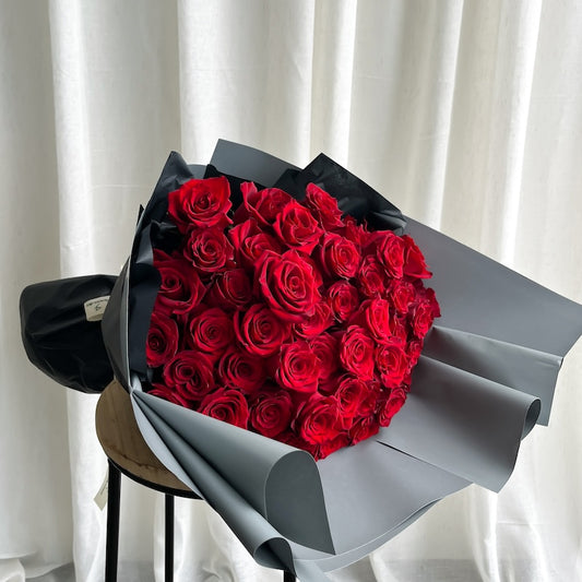 Bouquet of red roses wrapped in gray paper on a white background