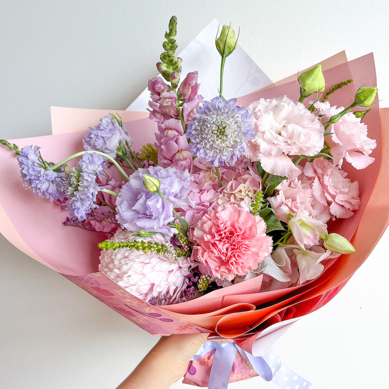 Pastel pink and purple flower bouquet with snapdradons, lisianthus, carnations, and disbud.